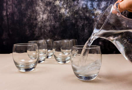 Mineral water from a pitcher poured into a glass.の写真素材