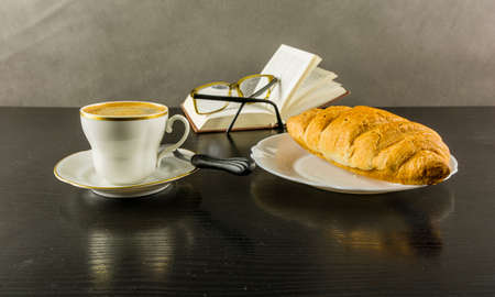Croissant and a cup of coffee during a break reading a book.の写真素材