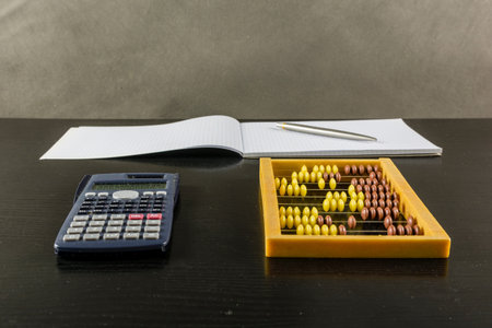 Abacus and calculator on a wooden dark desk.