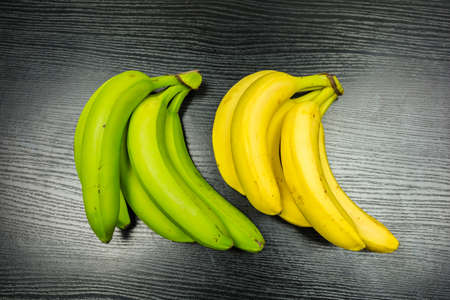 A bunch of bananas - green (unripe) and yellow (ripe).の写真素材