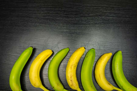 Yellow and green bananas on a wooden background.の写真素材