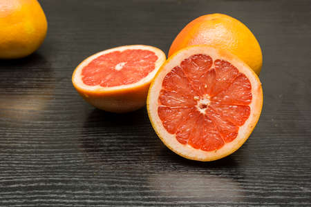 Ripe pink grapefruit cut in half on a wooden dark table.の写真素材