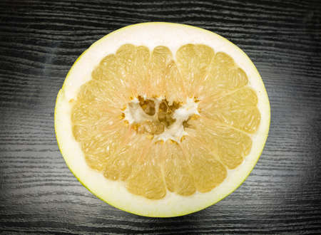 Split ripe fruit pomelo on a wooden dark table.の写真素材