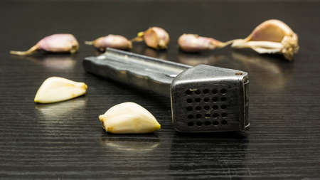 Peeled garlic clove and garlic press on a garlic table background.の写真素材