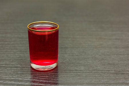 A glass of red sweet cherry liqueur on the table.
