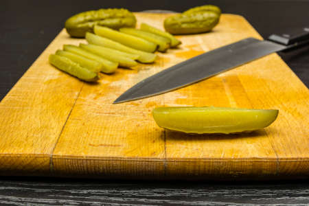 Prepared for dinner, pickled cucumbers cut into quarters on a chopping board.の写真素材