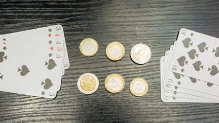 Spread out playing cards and euro coins on the table.