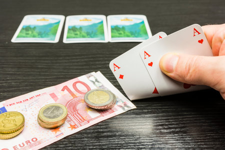 The poker player picks up two cards. He will bet money because he has a good cards, or two aces in...