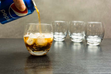 Niedomice, Poland - December 22, 2017: Pepsi from a can is poured into a glass with ice cubes.のeditorial素材