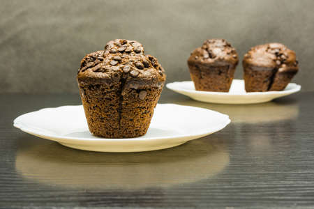 Chocolate cake (Muffin) on a white plate on a wooden table.の写真素材