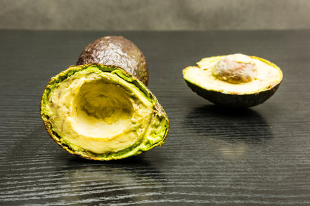 Cut in half Hass avocado on a wooden dark table.