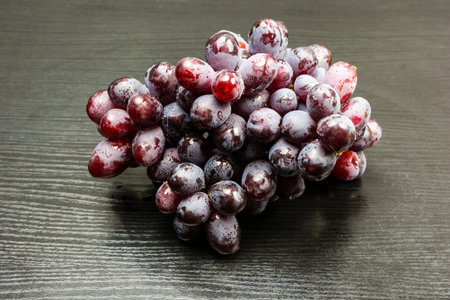 A red variety of grapes on a wooden table.