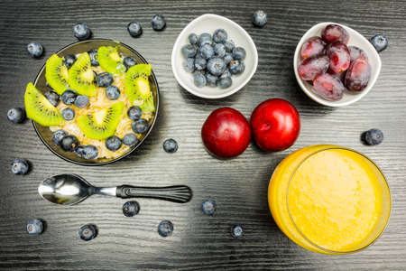 Healthy breakfast for children and adults. Oatmeal on milk with fruit, extra fruit for a snack and a glass with orange juice for drinking.の写真素材