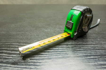 Self-retracting metal tape measure on a wooden dark table.
