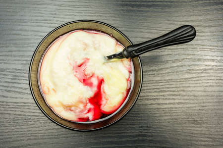 Cooked fresh creamy pudding with raspberry juice in a bowl on a wooden table. View from above.の写真素材