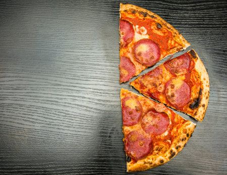 Half of pizza on a dark wooden background.