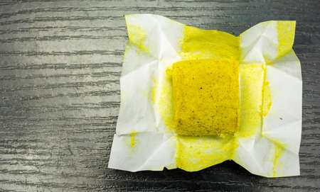 One cube of poultry bouillon with paper wrapperon a wooden background. View from above.の写真素材