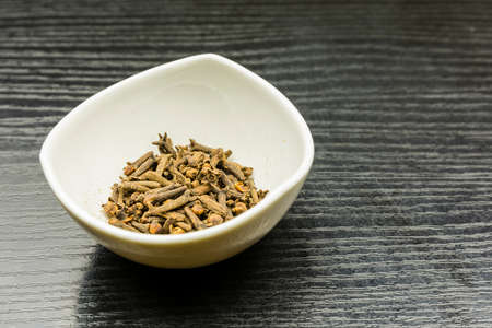 Dried cloves in a bowl on a wooden table.の写真素材