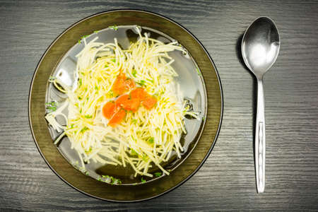 Plate of chicken noodle soup with orange carrot and green parsley. View from above.の写真素材