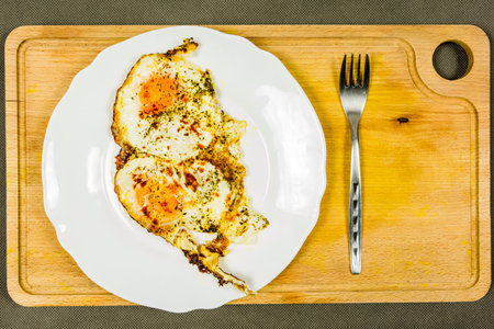 Fried egg with spices on a plate served on a wooden board.
