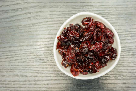 Bowl with dried cranberries on a dark table. View from above.の写真素材