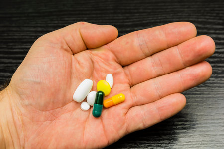 A collection of different pills and pills on the hand of a sick patient.