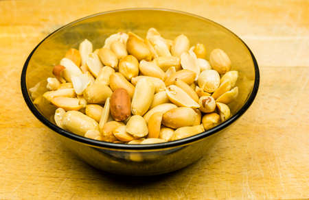 Bowl with shelled peanuts (groundnut, goober) on a wooden background.の写真素材