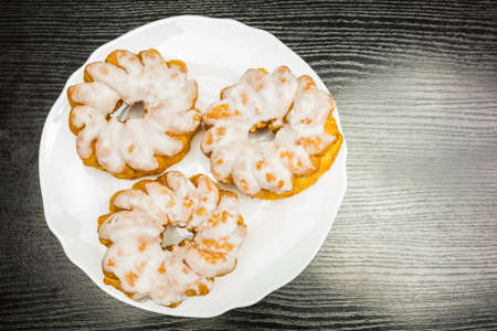 A plate with cakes poured with royal icing on a wooden table. View from above.の写真素材
