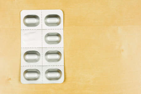 Blister pack with tablets on a wooden background.の写真素材