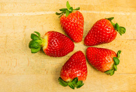 Red ripe strawberries on a wooden board, form a flower.の写真素材