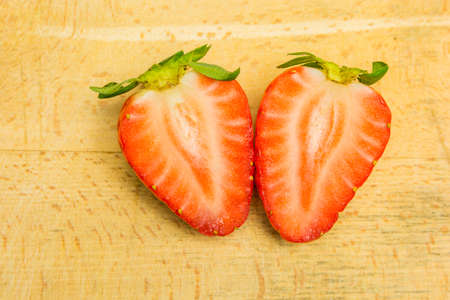 A red strawberry cut in half on a board.の写真素材
