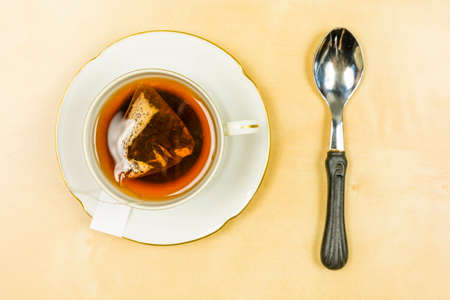 On the table a cup with freshly brewed tea from a bag and a teaspoon. View from above.の写真素材