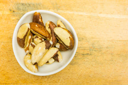 Bowl with brazil nuts after shell removal on a wooden background. View from above.の写真素材