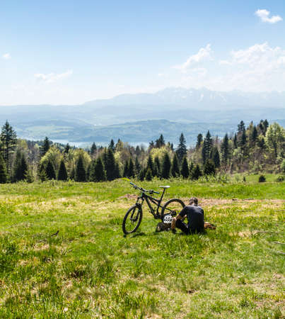 Ochotnica Gorna, Poland - May 03, 2018: Tired of riding a bicycle, a tourist rests from riding on a glade in the mountains.のeditorial素材