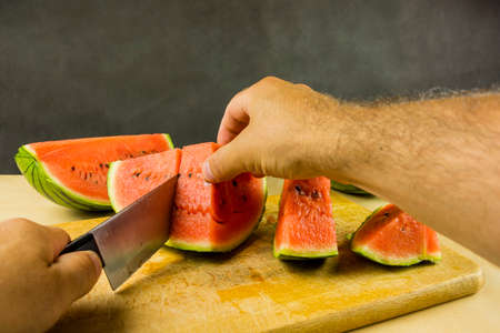 Slicing knife ripe red juicy watermelon on a chopping board.の写真素材