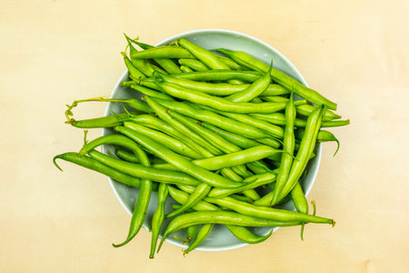 Green fresh green beans in a white bowl. View from above.