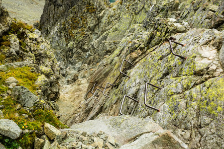 Metal buckles and a chain to help you overcome a steep and more difficult part of the trail in the mountains led by a gully.の写真素材