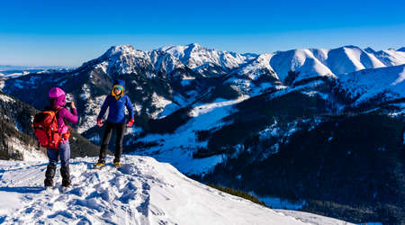 Witow, Poland - January 07, 2020: A friend takes a picture of a friend against the backdrop of mountains in winter scenery.のeditorial素材