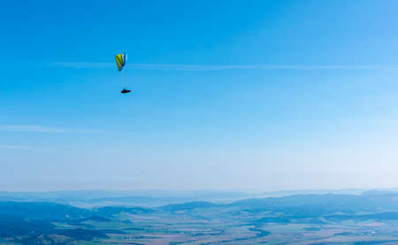 Tatranska Lomnica, Slovakia - September 15, 2020: Paragliding - A paraglider flying high above the valley on a beautiful sunny day.のeditorial素材
