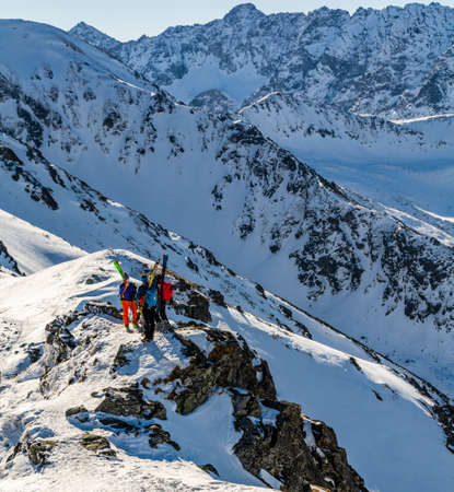 Zakopane, Poland - March 02, 2021: Ski touring, three skiers with skis attached to their backpacks on a rocky ridge. A break in the trip for a commemorative photo.のeditorial素材