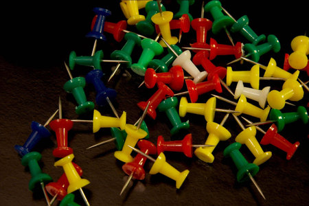 A pile of colourful pushpins on black background