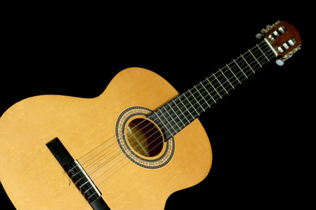 Neck and head of an acoustic guitar, isolated black background with copy-space
