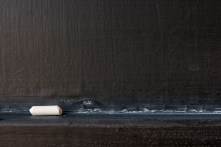 closeup of an empty blackboard with a piece of chalkの写真素材