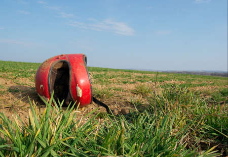 Red broken helmet  on an agricultural fieldの写真素材