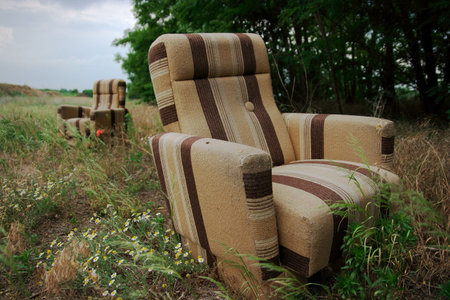Two discarded armchairs on a field