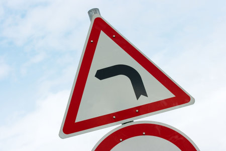 Road turns left traffic sign against blue sky