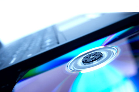 Laptop with open cd tray and a shiny disc in it in bluish tones
