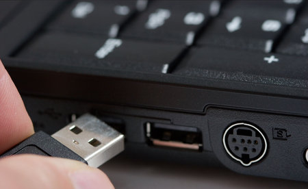 Hand plugging an usb plug into the socket of a laptop
