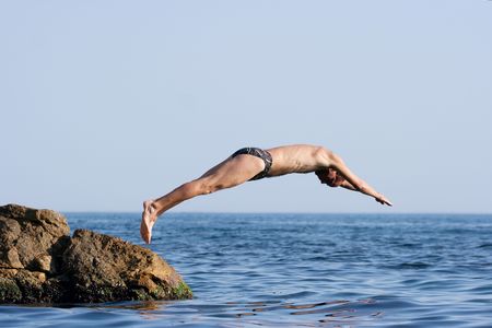 Man jumping headlong into the seeの写真素材