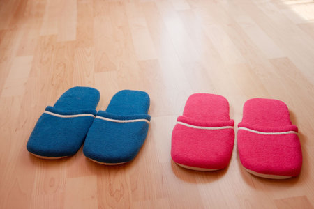 Two pairs of warm slippers on the parquetの写真素材